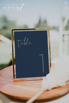 a table with a sign that says table 1 on it and a white feather sitting next to it