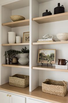 the shelves are filled with books, vases and other decorative items in white painted walls