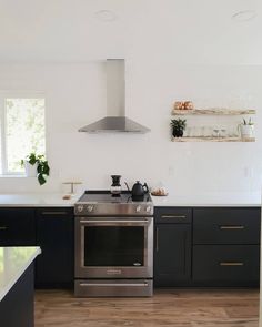 Modern black and white kitchen.  Black kitchen cabinets.  White subway tile. Kitchen floating shelf .