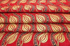 red and gold fabric with an intricate design on the bottom, along with other fabrics