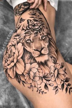 a woman's thigh with flowers and a lion tattoo on it