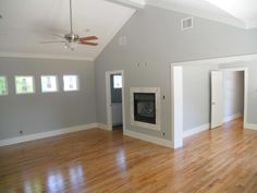 an empty living room with hard wood floors and white trim on the walls, two open closet doors, and a fireplace