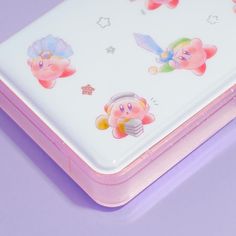 a pink and white lunch box with little pigs on it's lid, sitting on a purple surface