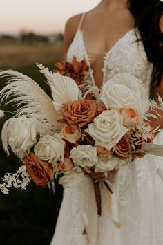 a bride holding a bouquet of white and orange flowers on her wedding day at sunset