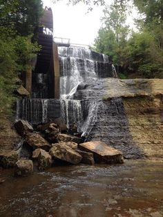 a large waterfall with lots of water coming from it's sides and some rocks in the foreground