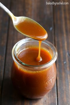 a spoon is pouring sauce into a jar