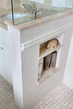 a bathroom with a sink, mirror and white brick fireplace in the middle of it