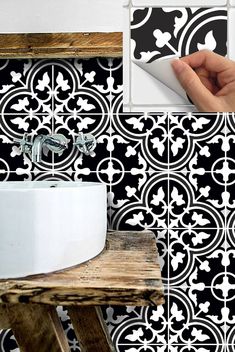 a bathroom with black and white tiles on the wall next to a hand holding a brush