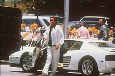 a man standing next to a white sports car