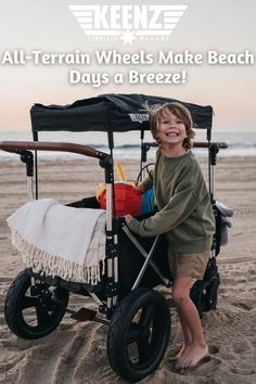 A Keenz 7S 2.0 2-Passenger Stroller Wagon with a boy standing next to it. The stroller is filled with beach gear. Keenz. All-terrain wheels make beach days a breeze! Sport Event, Beach Day, The Park, Cup Holder, Passenger, The Original