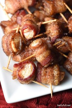 bacon wrapped in toothpicks on a white plate with a red towel behind it