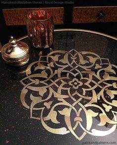 a table with a glass top that has an intricate design on it and the words, stenciling on the reverse side of glass to make a beautiful table top