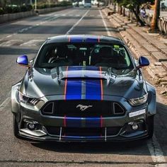 the front end of a gray mustang with blue and red stripes