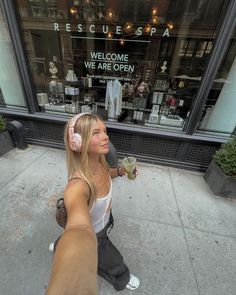 a woman is walking down the sidewalk with headphones in her ears and looking up