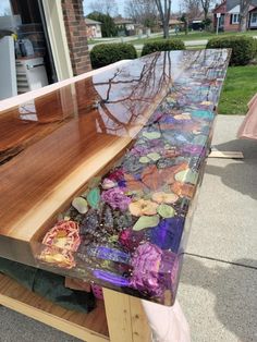 a wooden table with glass top sitting on the side of a sidewalk next to a building