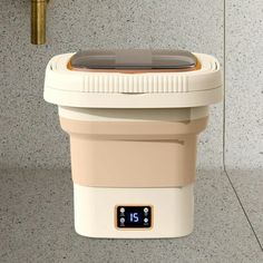 a white and beige cooler sitting on top of a counter next to a faucet