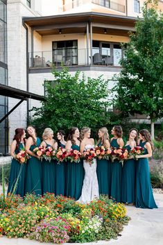 a group of women standing next to each other in front of a building with flowers