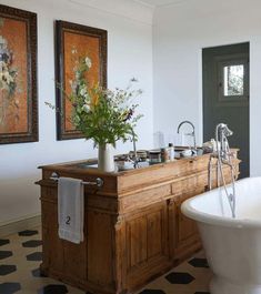 a bathroom with an old fashioned bathtub and flowers on the counter top in front of it