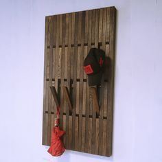 a hat and umbrella hang on a wooden wall with two hats hanging from it's hooks