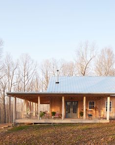 a small wooden cabin in the woods with a porch and covered veranda area on one side