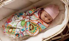 a baby is laying in a basket wearing a hat