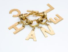 Chanel Letter Charm Bracelet Iconic and rare Chanel gold plated letter charm bracelet from Spring 1993 Collection. Chain link bracelet features toggle clasp. Comes with box. Approximate Measurements: Length 7.5”, Width 2.8” Made in: France.Thanks for viewing this item: we have more Chanel jewelry here. To find out more about Chanel's history please visit our blog. Luxury Gold-tone Jewelry With Logo Lettering, Formal Yellow Gold Jewelry With Gold-tone Logo Lettering, Designer Yellow Gold Jewelry With Logo Lettering, Designer Gold Bracelets With Logo Charm, Designer Gold-tone Logo Bracelets As Gift, Modern Gift Jewelry With Gold-tone Logo Plaque, Modern Jewelry With Gold-tone Logo Plaque As Gift, Vintage Gold Bracelet With Logo Charm, Designer Gold-tone Bracelets For Gift