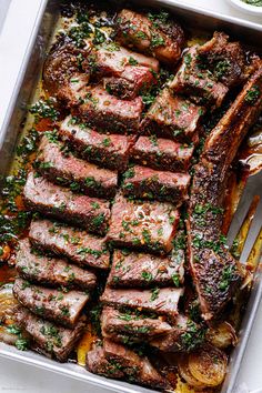 a pan filled with steak and potatoes on top of a table next to a knife