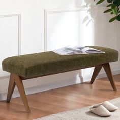 a wooden bench sitting on top of a hard wood floor next to a potted plant