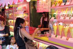 a woman standing in front of a store filled with ice cream cones and small children