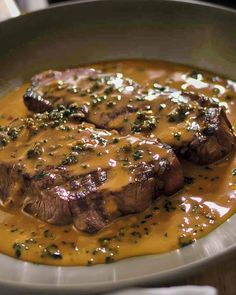 steak with gravy in a white bowl on a table