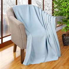 a chair with a blanket on it next to a potted plant