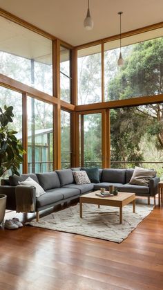 a living room filled with lots of windows and furniture next to a large wooden floor