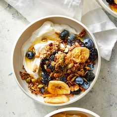 two bowls filled with yogurt, granola and fruit