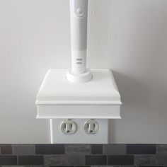 an electric toothbrush holder on top of a white wall with two plugs in front of it