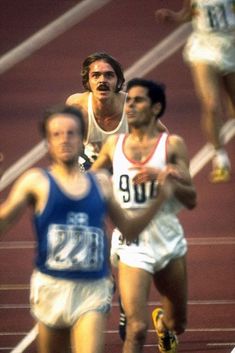 three men running on a track during a race