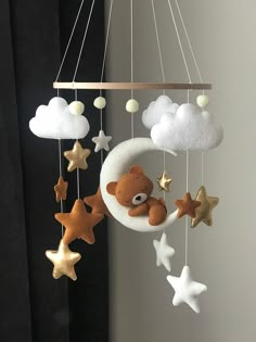 a teddy bear is sitting on the moon and stars hanging from it's sides