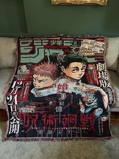 a blanket with anime characters on it sitting in front of a couch next to a painting