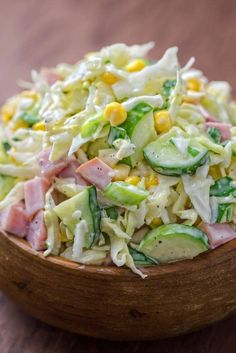 a wooden bowl filled with coleslaw salad on top of a wooden table next to a fork