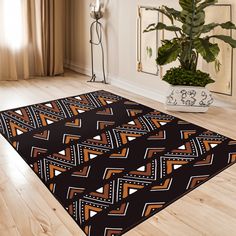 a black and orange area rug with an abstract design on the floor next to a potted plant