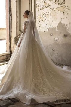 a woman in a wedding dress standing near a window