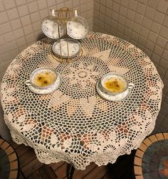 two bowls with food on them are sitting on a doily covered table in the corner