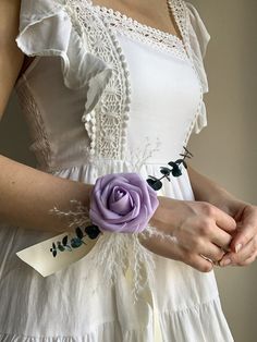 a woman wearing a white dress holding a purple flower