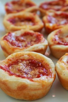 several mini pizzas on a white plate with red sauce in the middle and one inside