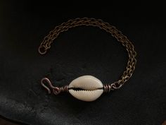 "This beautiful cowrie shell is wire wrapped with pure organic copper. The chain is vintage stock and made of solid brass. The metals have been oxidized for a rustic / tribal feel. All jewelry from my studio is endowed with a lifetime craftsmanship guarantee & arrives attractively packaged and ready for gifting or keeps. MEASUREMENTS & SPECIFICS: LENGTH: 7.25\" can be adjusted upon request METAL: solid vintage brass chain w/ hand forged copper hook / wire wrapping GEMSTONE: cowrie shell Bohemian Metal Shell Jewelry, Artisan Shell Jewelry With Adjustable Fit, Artisan Adjustable Shell Jewelry, Handmade Copper Jewelry For Beach, Handmade Copper Jewelry For The Beach, Beach Wire Wrapped Metal Jewelry, Bohemian Shell-shaped Brass Jewelry, Bohemian Shell Shaped Brass Jewelry, Handmade Bronze Jewelry For Beach