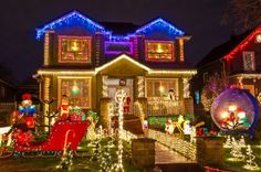 christmas lights on houses and lawns in front of the house at night with snow globe