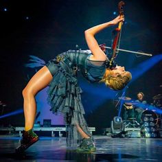 a woman is performing on stage with her legs in the air while holding onto a pole