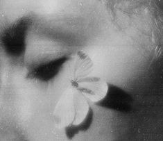 a black and white photo of a woman's face with a flower in her hair