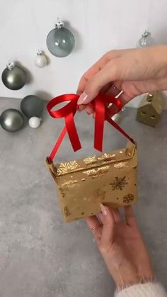 a person holding a gold gift box with red ribbon