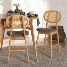 a dining table with two chairs and a basket on the floor in front of it