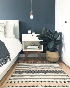 a white bed sitting next to a green plant on top of a wooden floor in a bedroom